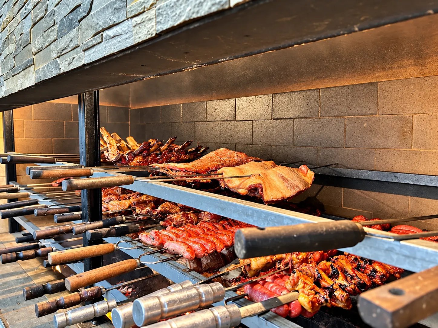 Churrasqueira com espetos de costela, frango, linguiça e picanha assando na brasa